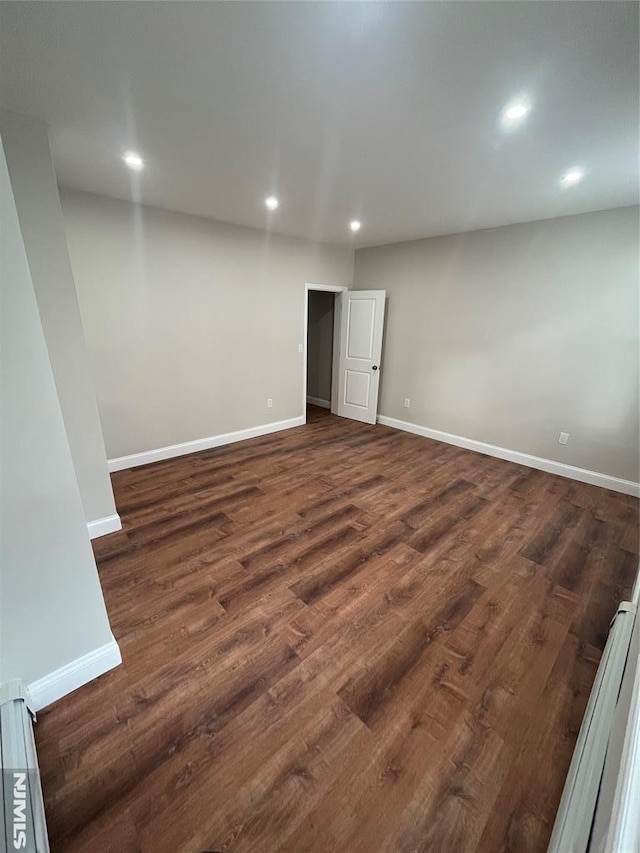 empty room with dark wood-type flooring, recessed lighting, and baseboards