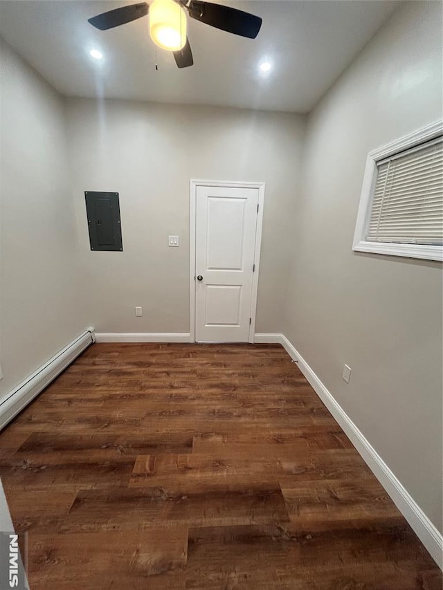 spare room featuring a ceiling fan, baseboards, electric panel, dark wood-style flooring, and baseboard heating