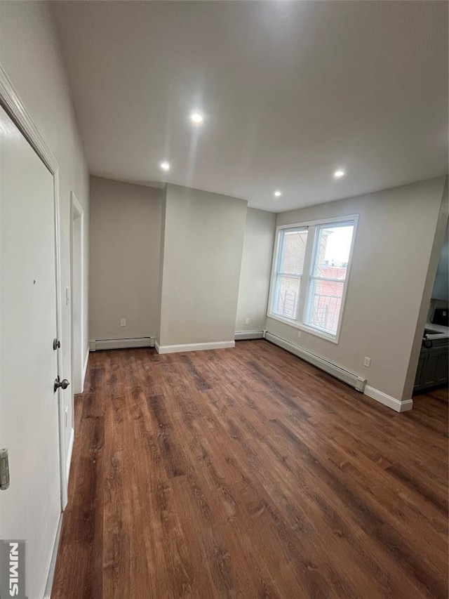 empty room with recessed lighting, dark wood-style floors, baseboards, and baseboard heating