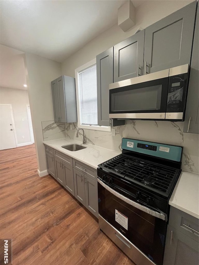 kitchen with tasteful backsplash, gray cabinets, stainless steel appliances, and a sink