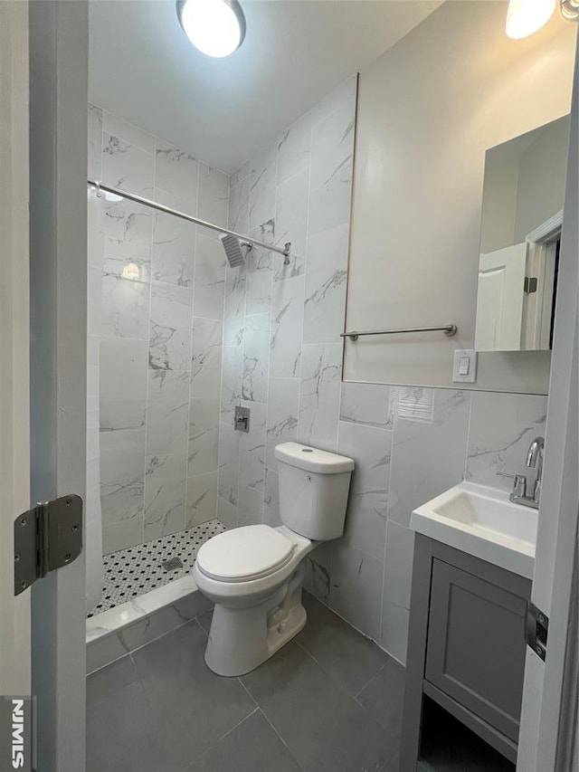 full bathroom with vanity, tile walls, a shower stall, and toilet