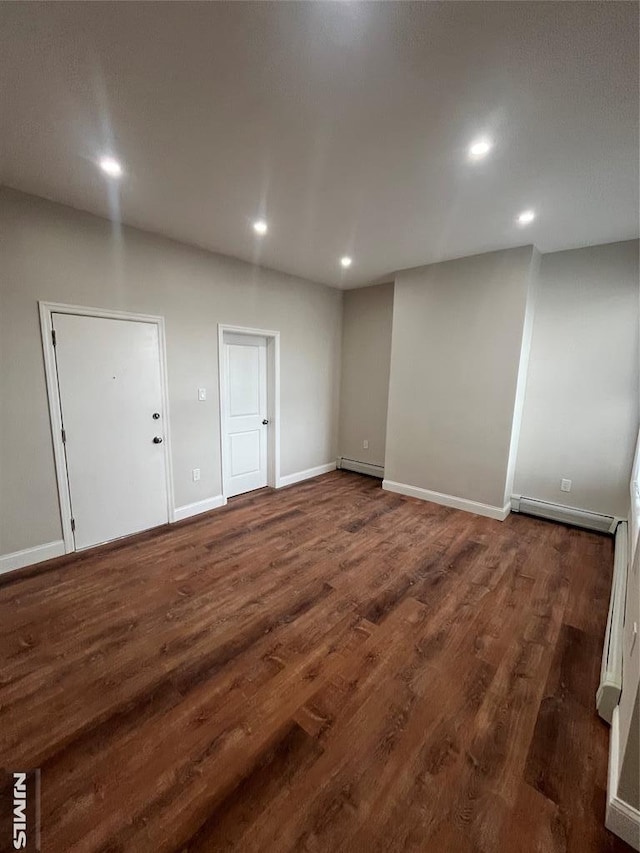 below grade area with a baseboard heating unit, recessed lighting, dark wood finished floors, and a baseboard radiator