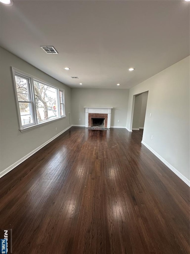 unfurnished living room featuring visible vents, dark wood-type flooring, recessed lighting, a fireplace, and baseboards