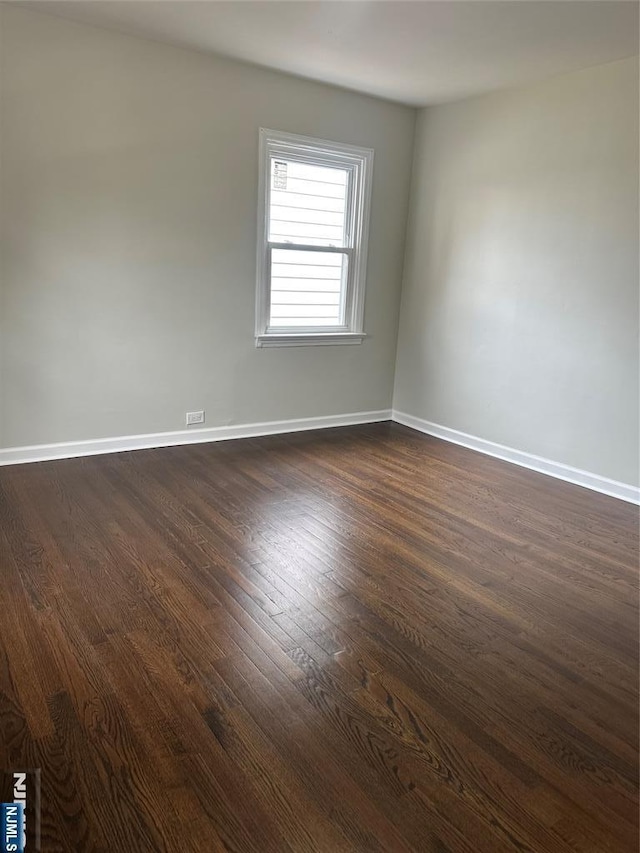 spare room featuring dark wood-type flooring and baseboards