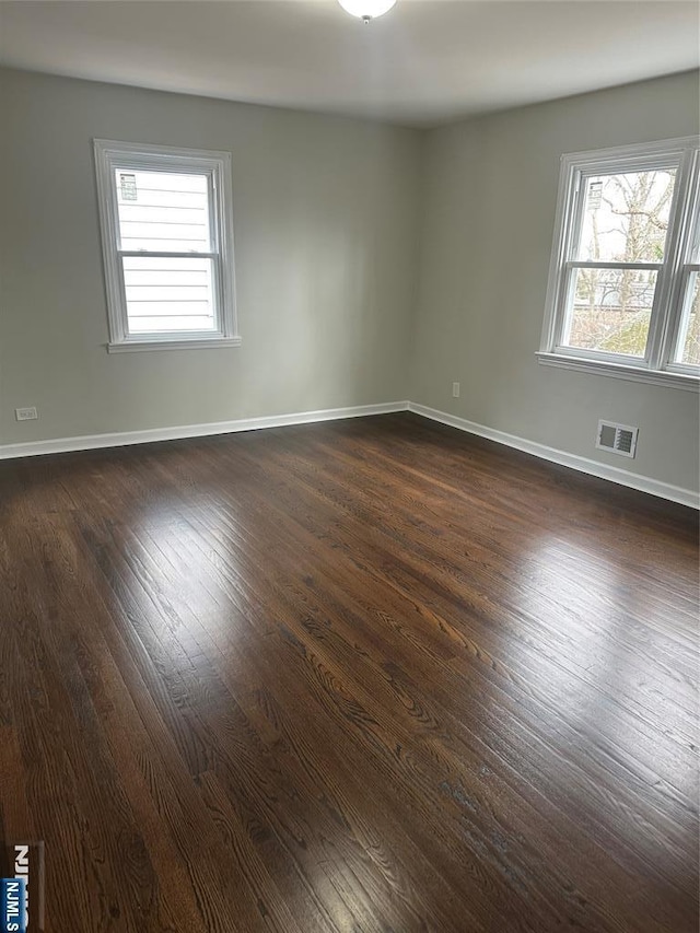 empty room featuring a wealth of natural light, visible vents, and baseboards