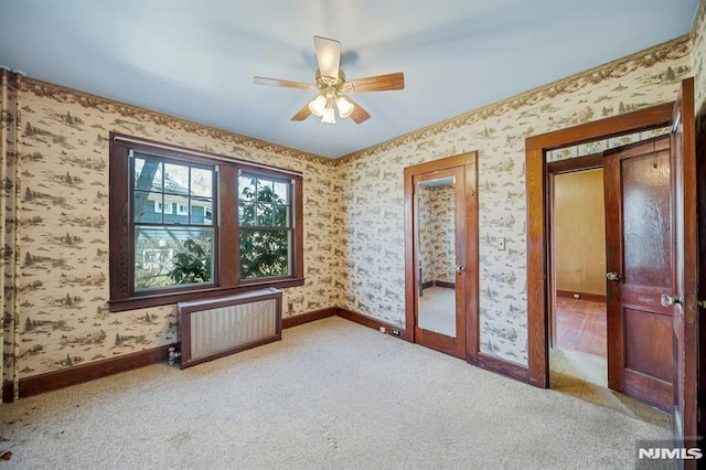 carpeted spare room featuring wallpapered walls, radiator, and baseboards