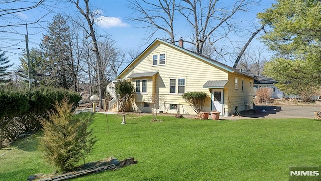 rear view of property featuring a lawn and a chimney