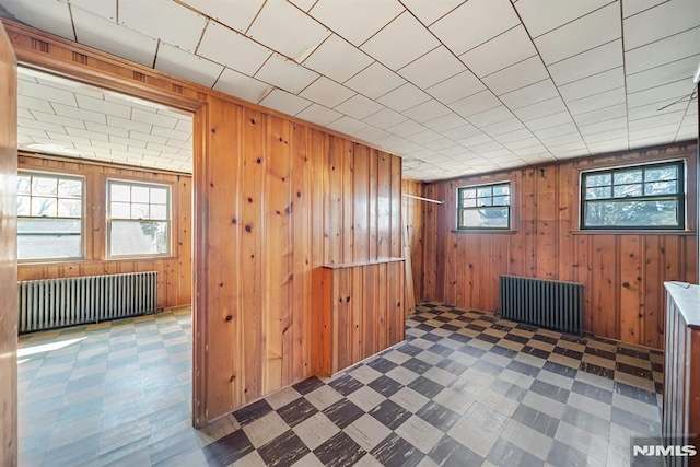 interior space with tile patterned floors, wood walls, and radiator