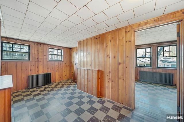 interior space featuring tile patterned floors, wooden walls, and radiator heating unit