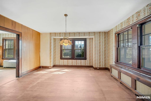 unfurnished dining area with light wood-style flooring, radiator, wallpapered walls, and baseboards