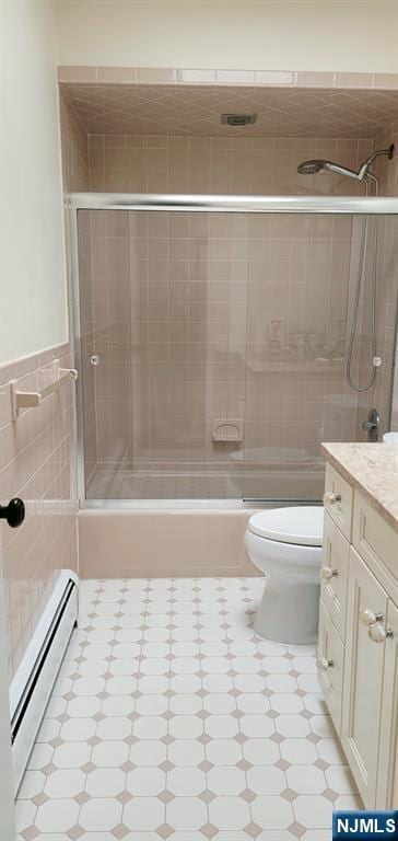 full bath featuring tile walls, toilet, vanity, and a baseboard radiator