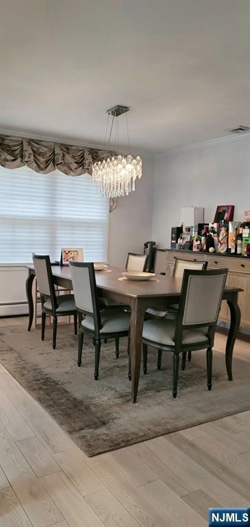 dining space featuring visible vents, light wood-style floors, and crown molding