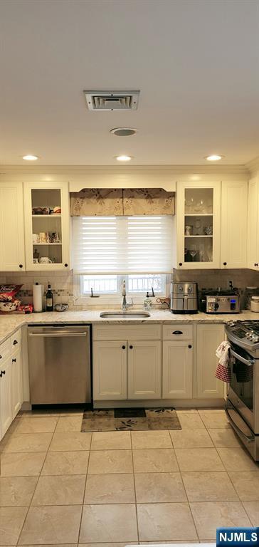 kitchen with visible vents, a sink, stainless steel appliances, light countertops, and backsplash