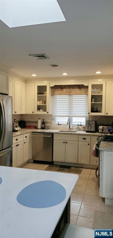 kitchen with visible vents, a sink, light countertops, glass insert cabinets, and appliances with stainless steel finishes