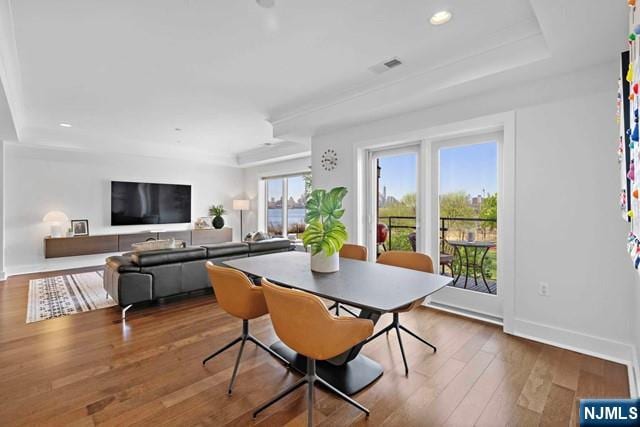 dining space featuring visible vents, baseboards, recessed lighting, wood-type flooring, and a raised ceiling