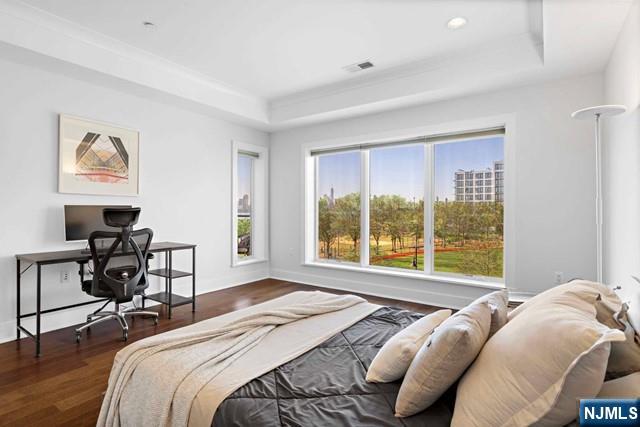 bedroom with visible vents, a raised ceiling, and wood finished floors