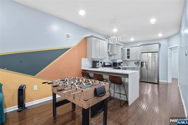 kitchen with backsplash, glass insert cabinets, dark wood finished floors, a peninsula, and stainless steel refrigerator with ice dispenser