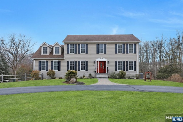 colonial home featuring a front lawn, fence, and driveway