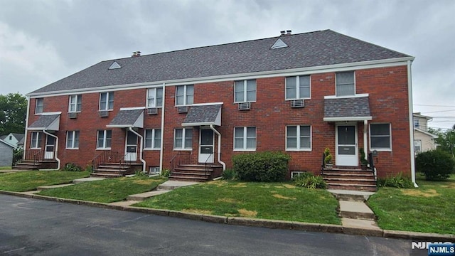 multi unit property with a front yard, brick siding, and a shingled roof