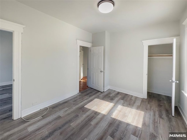 unfurnished bedroom with a closet, baseboards, and wood finished floors