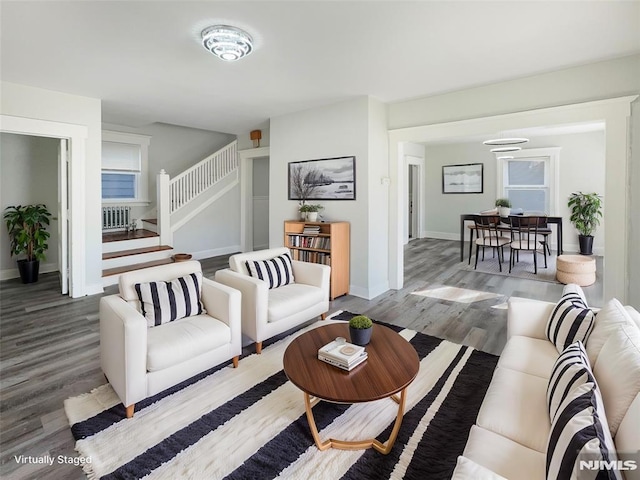 living room featuring baseboards, wood finished floors, and stairs