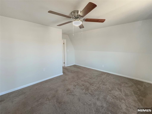 empty room with ceiling fan, carpet, baseboards, and vaulted ceiling