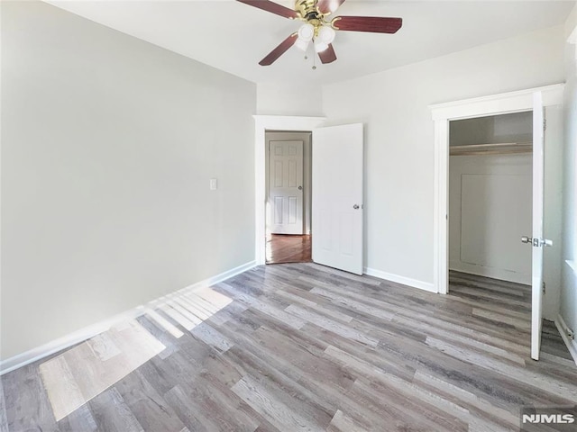 unfurnished bedroom with a closet, ceiling fan, baseboards, and wood finished floors