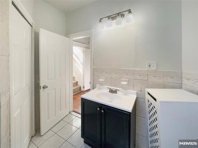 bathroom with tile patterned flooring, tile walls, vanity, and a wainscoted wall