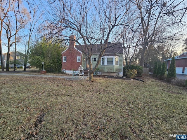 bungalow-style home featuring a chimney, a front yard, and entry steps