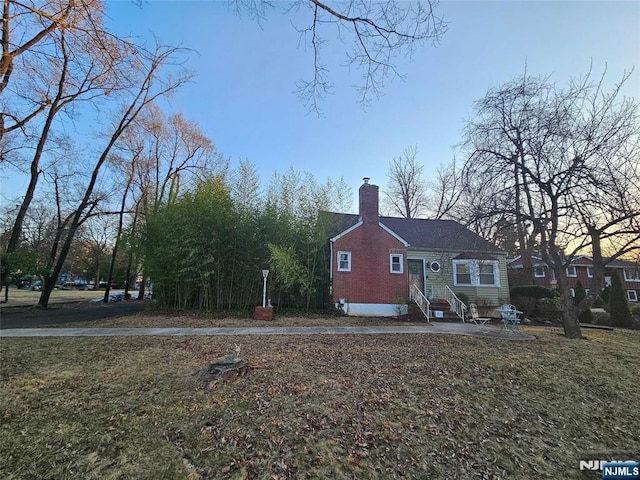 view of home's exterior with brick siding, a chimney, and entry steps