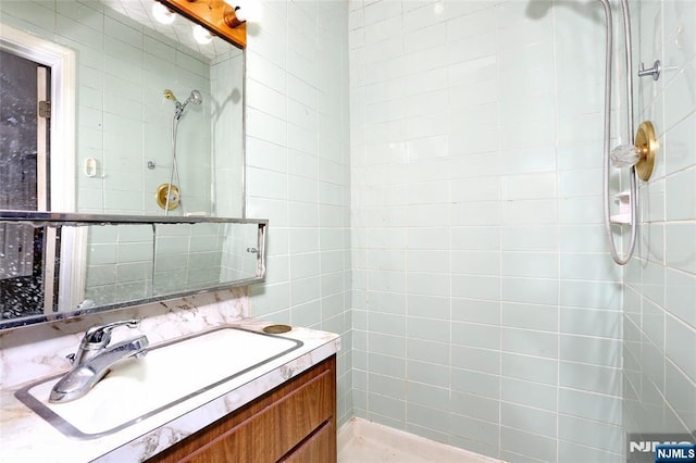 full bath with vanity, tile walls, and tiled shower