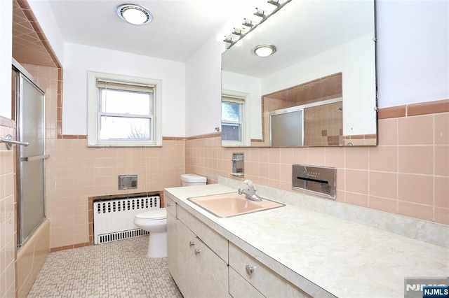 full bath with vanity, radiator, tile patterned flooring, tile walls, and toilet