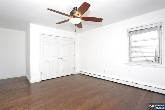 unfurnished bedroom with a baseboard heating unit, baseboards, a closet, and dark wood-style floors