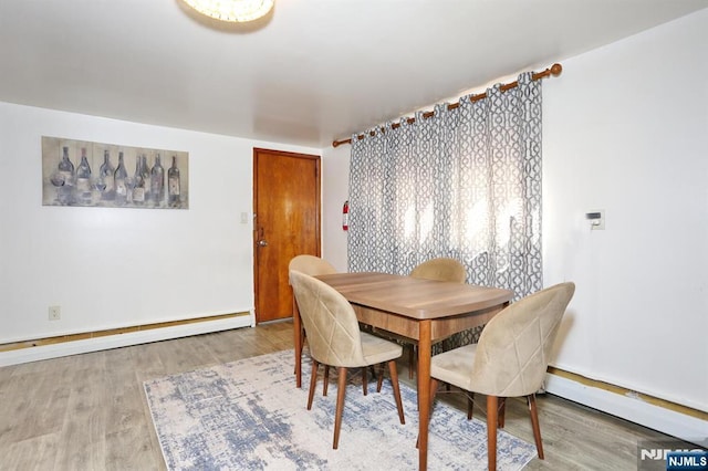 dining area with a baseboard heating unit and wood finished floors