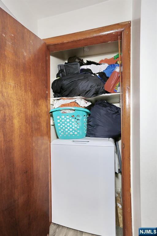 clothes washing area featuring laundry area, wood finished floors, and washer / dryer