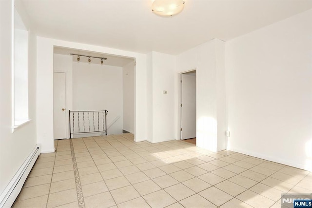 empty room featuring light tile patterned floors and a baseboard radiator