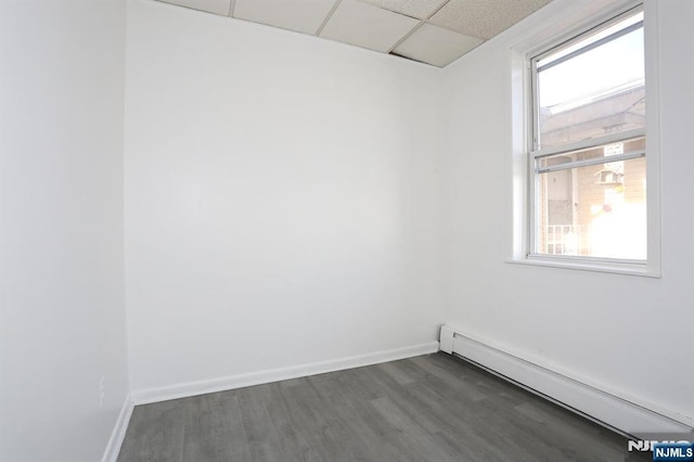 unfurnished room with a drop ceiling, a healthy amount of sunlight, baseboards, and baseboard heating