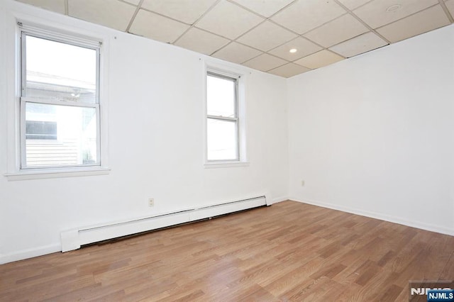 spare room featuring light wood finished floors, a paneled ceiling, baseboards, and baseboard heating