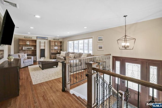 living area featuring visible vents, ornamental molding, wood finished floors, recessed lighting, and an inviting chandelier