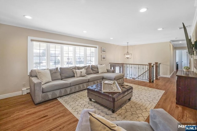 living area featuring a baseboard heating unit, wood finished floors, and baseboards