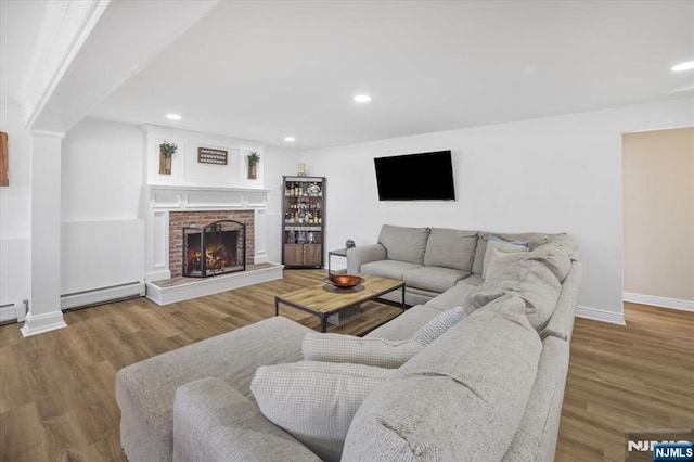 living room with wood finished floors, recessed lighting, a fireplace, baseboards, and baseboard heating