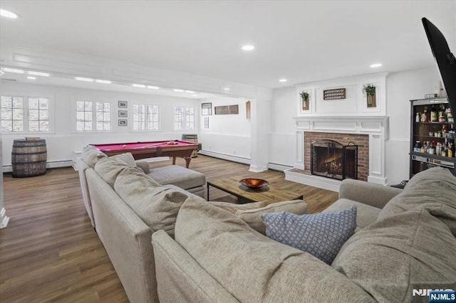 living room with baseboard heating, wood finished floors, and a fireplace