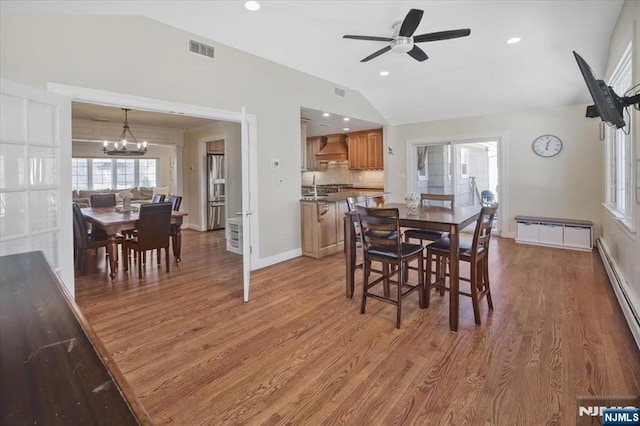 dining space featuring visible vents, baseboards, lofted ceiling, baseboard heating, and light wood-style floors