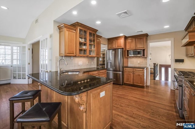 kitchen featuring brown cabinetry, vaulted ceiling, stainless steel appliances, and a sink