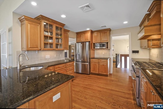 kitchen with visible vents, glass insert cabinets, appliances with stainless steel finishes, wood finished floors, and a sink