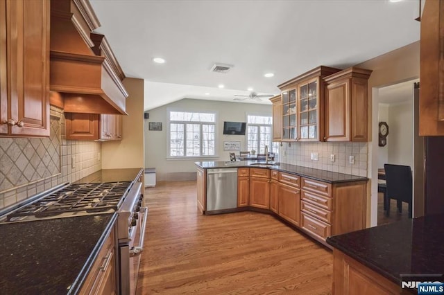 kitchen featuring a ceiling fan, light wood-style flooring, a sink, glass insert cabinets, and appliances with stainless steel finishes