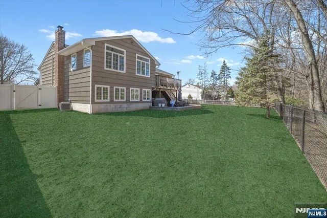 back of house with central AC unit, a lawn, a chimney, a fenced backyard, and a gate