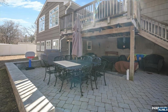 view of patio with stairs, outdoor dining area, and fence