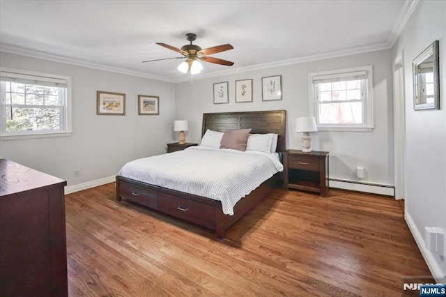 bedroom featuring crown molding, ceiling fan, a baseboard heating unit, baseboards, and wood finished floors