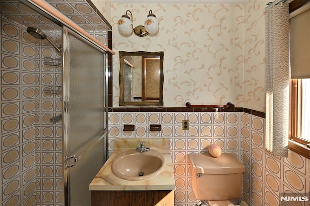 bathroom with toilet, a stall shower, vanity, and wallpapered walls